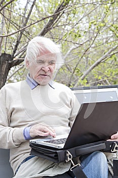 Senior man using laptop computer outdoors