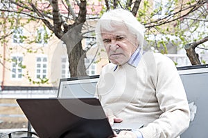 Senior man using laptop computer outdoors