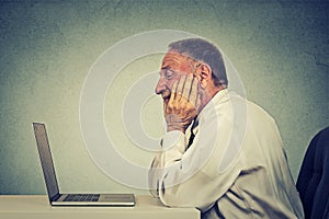 Senior man using laptop computer reading email news.