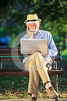 Senior man using laptop computer at rest in the park outdoors