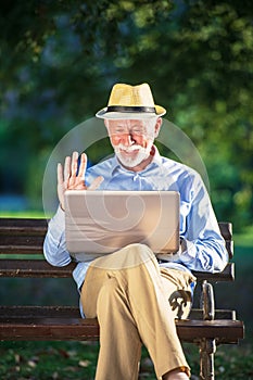 Senior man using laptop computer at rest in the park outdoors