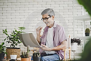 Senior man is using laptop computer for Video calling to family in home garden