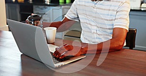 Senior man using laptop while having coffee