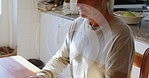 Senior man using laptop in kitchen 4k