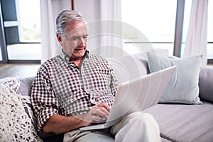 Senior man using laptop in living room