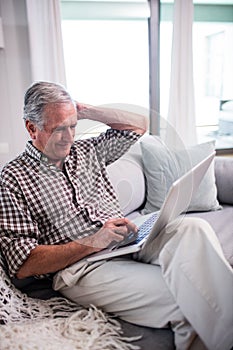 Senior man using laptop in living room