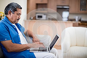 Senior man using laptop in living room
