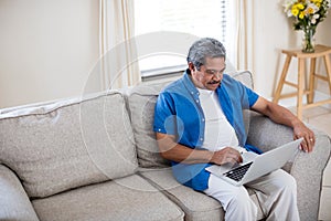 Senior man using laptop in living room