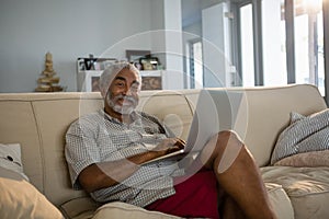 Senior man using laptop in the living room