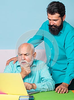 Senior man using laptop PC with his adult son. Friends senior father and adult son taking a break after meeting session