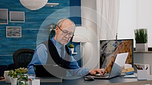 Senior man using laptop and tablet in same time