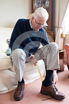 Senior Man Using Long Handled Shoe Horn To Put On Shoes