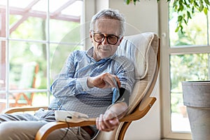 Senior man using medical device to measure blood pressure