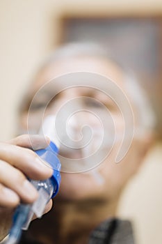 Senior man using medical equipment for inhalation with respiratory mask, nebulizer