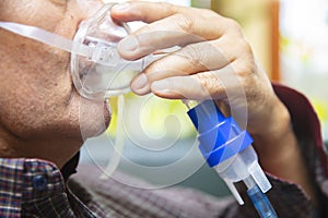 Senior man using medical equipment for inhalation with respiratory mask, nebulizer