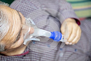 Senior man using medical equipment for inhalation with respiratory mask, nebulizer