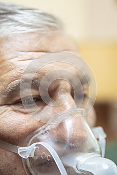 Senior man using medical equipment for inhalation with respiratory mask, nebulizer