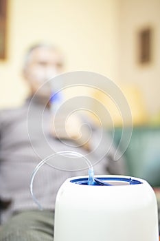 Senior man using medical equipment for inhalation with respiratory mask, nebulizer