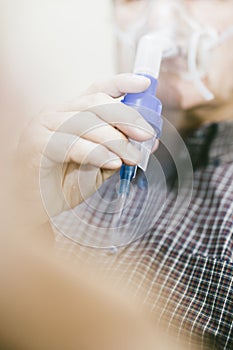 Senior man using medical equipment for inhalation with respiratory mask, nebulizer