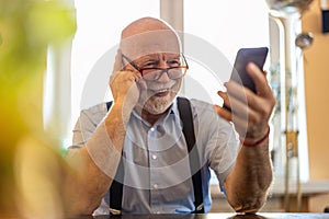 Senior man using a mobile phone at home