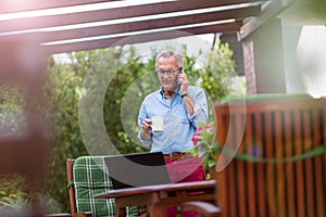 Senior man using mobile phone in backyard photo
