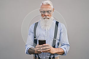 Senior man using mobile smartphone and listening music with airpods - Fashion bearded male working on digital marketing social