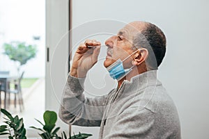 Senior man using an nasal swab for covid 19 detection