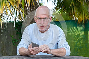 Senior man using phone in the garden