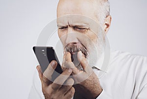 Senior man using a phone and having eyesight problems