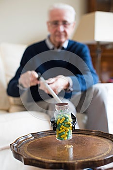 Senior Man Using Reaching Arm To Pick Up Medication At Home