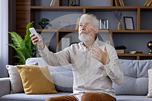 Senior man using remote control for air conditioning at home