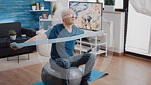 Senior man using resistance band to do physical exercise