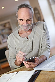 Senior man using smartphone at home