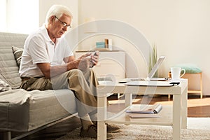 Senior Man Using Smartphone at Home