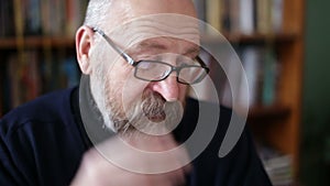 Senior man using tablet sitting on on a chair in the library