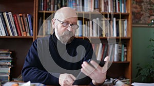 Senior man using tablet sitting on on a chair in the library