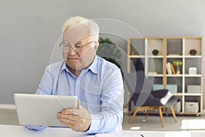 Senior man using tablet to book medical appointment, check pension plan or read news