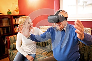 Senior man using virtual reality simulator and having fun with n