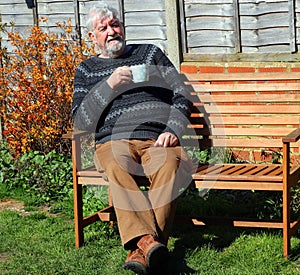 Senior man very relaxed with a coffee or tea outside.