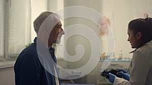 Senior man visiting cardiologist in clinic close up. Woman doctor checking pulse