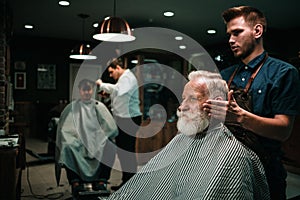 Senior man visiting hairstylist in barber shop.