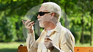 Senior man with visual impairment talking through speakerphone, voice commands