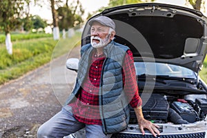 Senior man waiting for help beside car with open hood