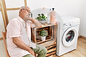 Senior man waiting for washing machine sleeping on chair at laundry room