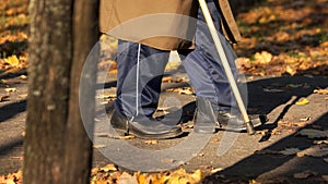 Senior man walking with cane in autumn park.