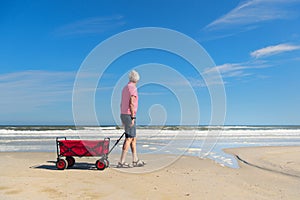 Senior man walking with cart at the beach