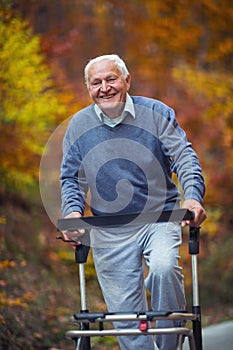 Senior man with a walking disability enjoying a walk in an autumn park