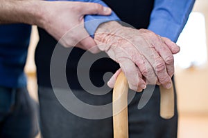 Senior Man With Walking Stick Being Helped By Care Worker photo