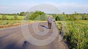 Senior man with walking stick walking on a country road