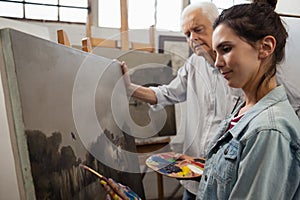 Senior man watching while artist painting on canvas